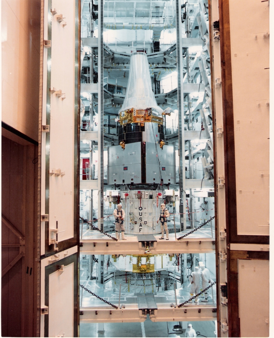 Large-format photograph: Shuttle Payload Integration Facility (SPIF) Integration Cell. You're looking directly at the Cap Rails, visible as gray vertical bars on either side of the IUS and the DSP satellite which is sitting on top of it, extending out of frame, top and bottom. Immediately outboard of the Cap Rails, the uncovered portion of the near-side flange of the Longeron Columns is clearly visible, painted white. That my memory of the look and aspect of those Cap Rails, forty full years later, is as impossibly, near-photographically, accurate as it is, leaves me so gobsmacked as to render me speechless. For myself, this is a powerfully-emotional photograph, on more levels than I could ever list, define, or describe. So I shall leave it in peace.